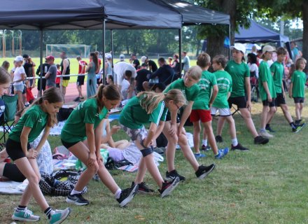 Trainingsgruppe bei der Mobilisierung auf dem Rasen mit Zuschauern und dem Sportplatz im Hintergrund